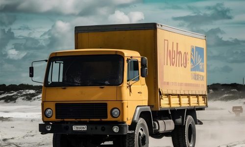 yellow-truck-riding-sandy-ground-cloudy-blue-sky (1)